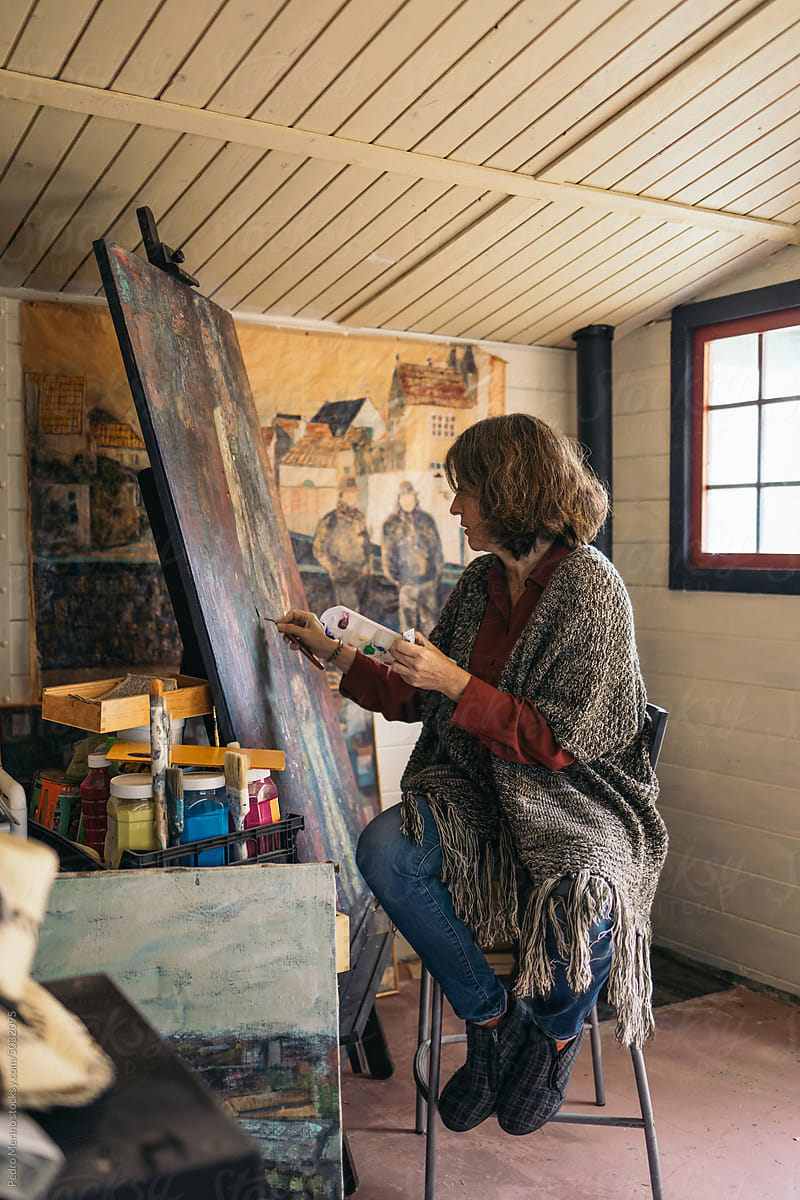 Mature woman artist painting in a small painting workshop