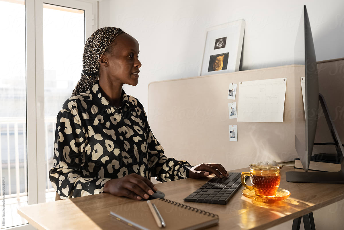 Black freelancer using desktop during teatime