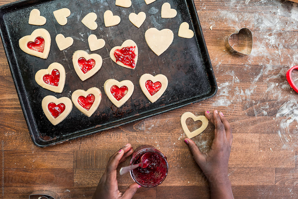 Black girl\'s hands with heart shaped cookies in a tray