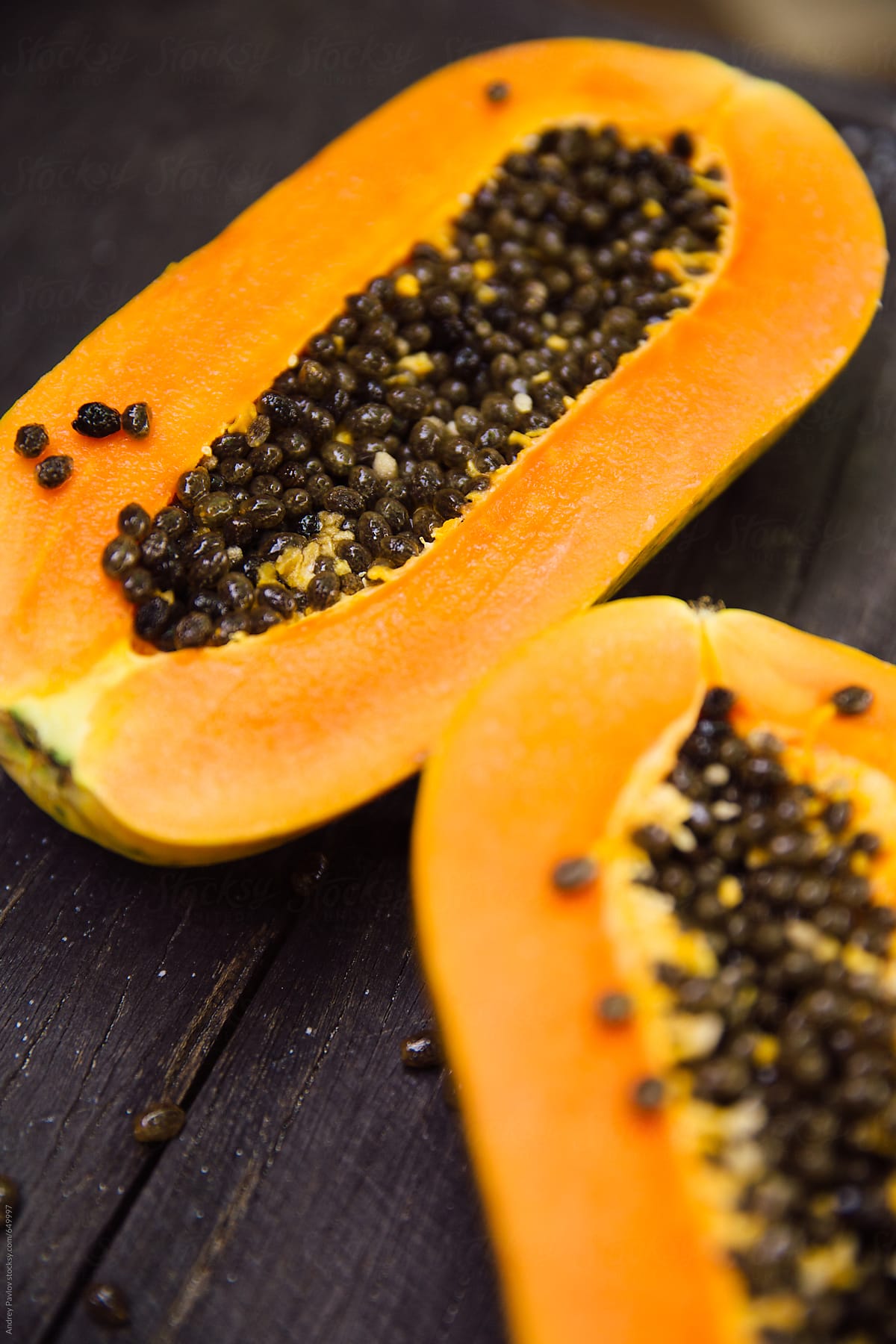 Two parts of a papaya fruit with seeds