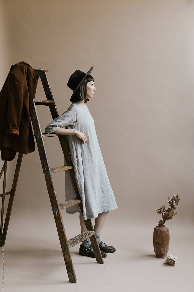 Woman In Grey Dress And Hat Posing Next 