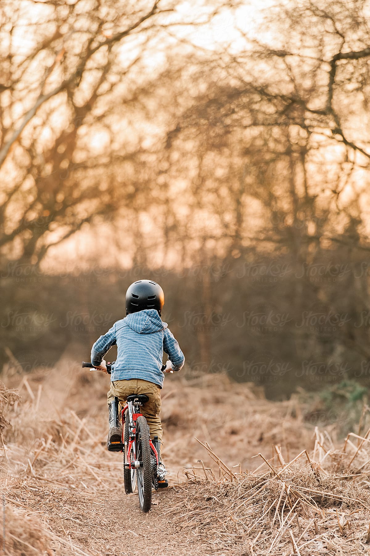 Rear view of boy on red bike with cycle helmet
