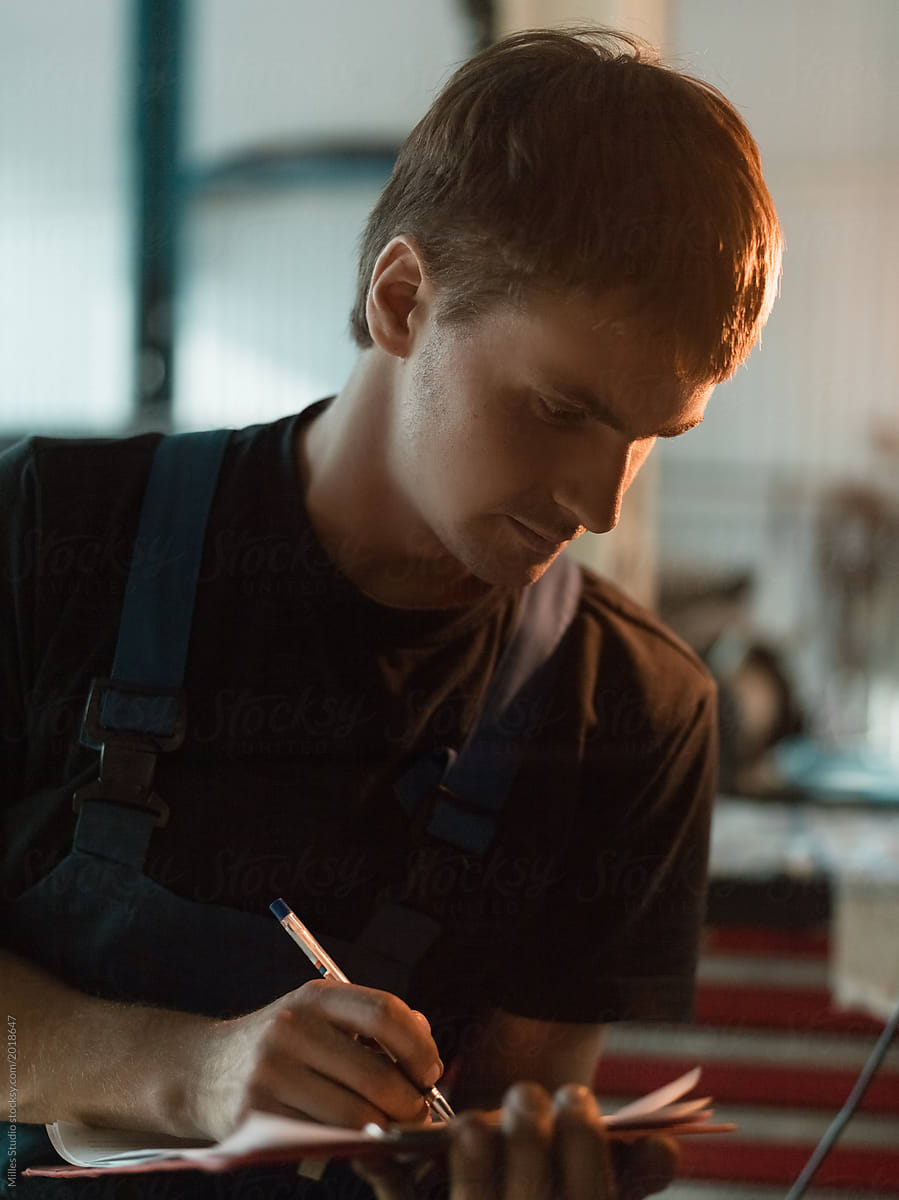 Workman writing on clipboard in garage