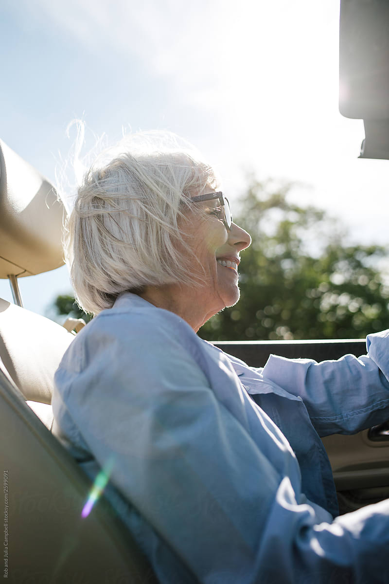 Relaxed older woman driving convertable car.