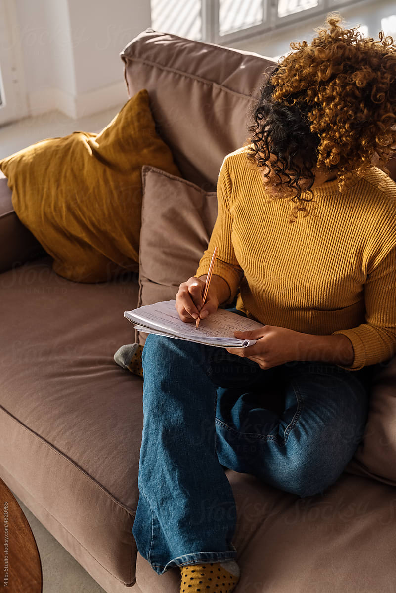 Female sitting on sofa and making notes