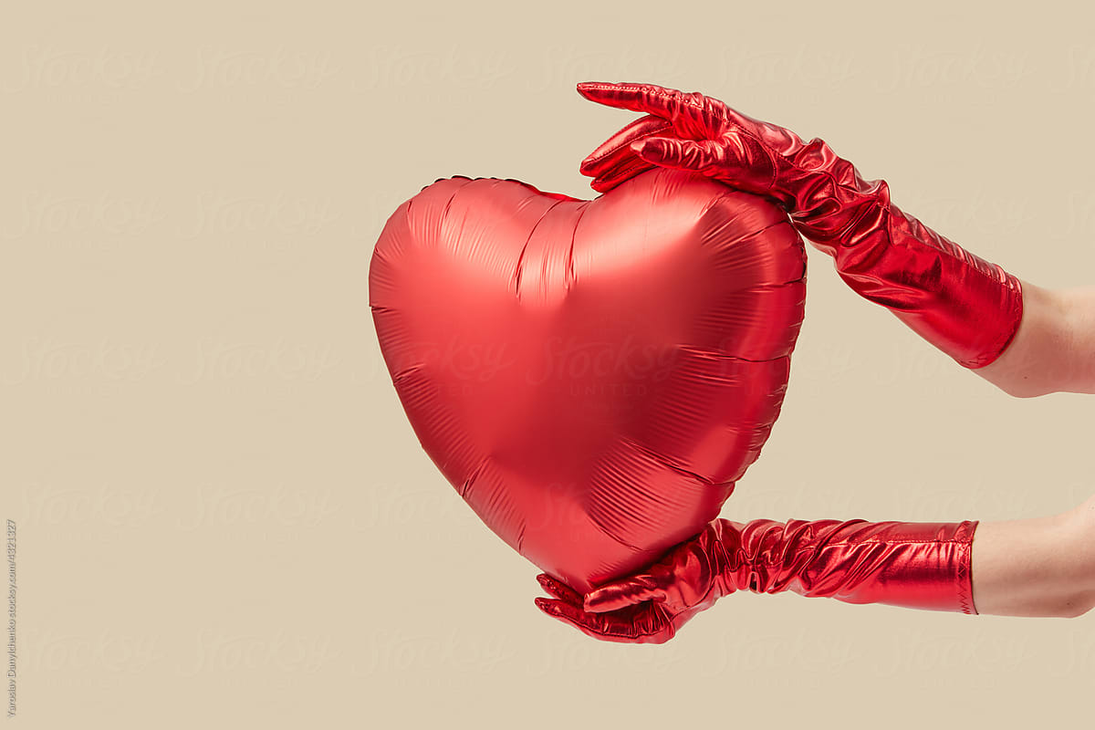 Woman in gloves holding heart balloon