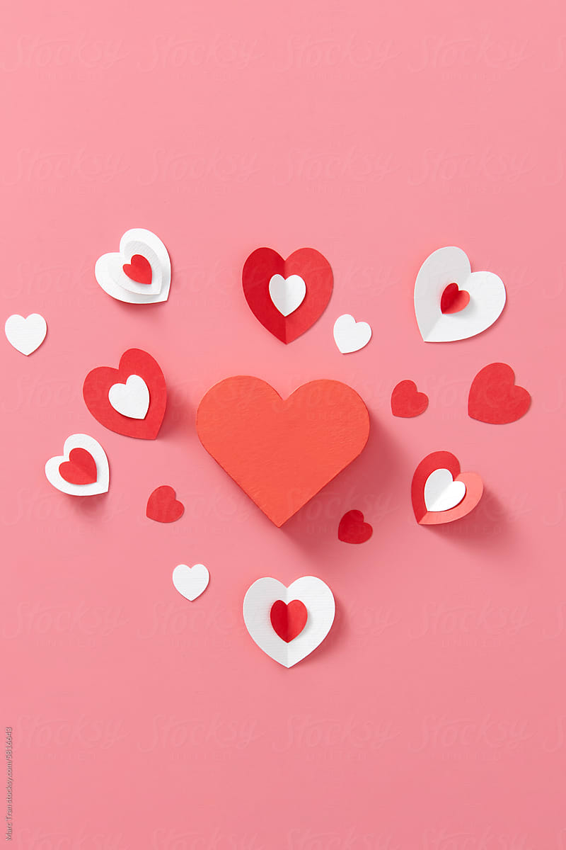 Flying red paper hearts on pink background. Valentine\'s Day.