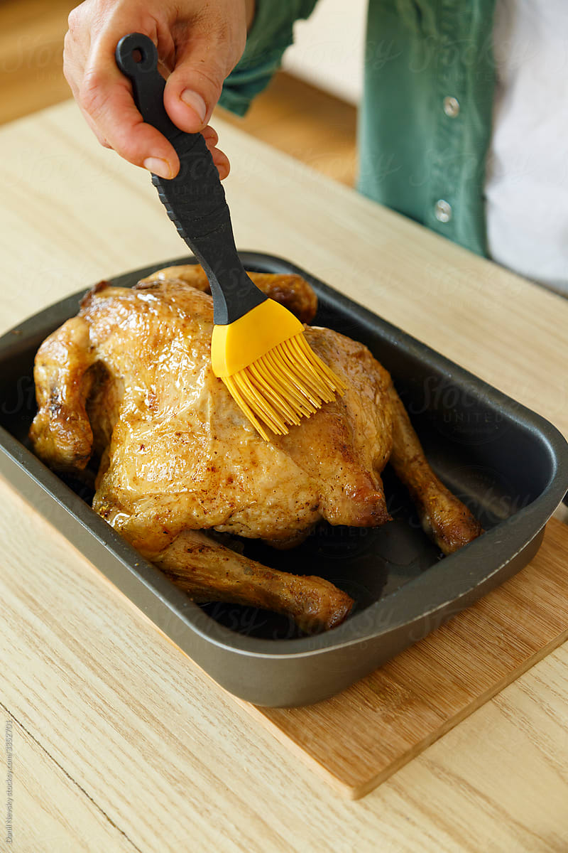 Crop person spreading oil on chicken