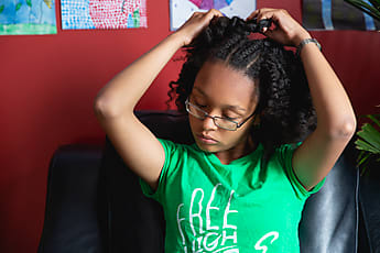 Portrait Of A Pretty Teenager As She Combs Her Kinky Curly