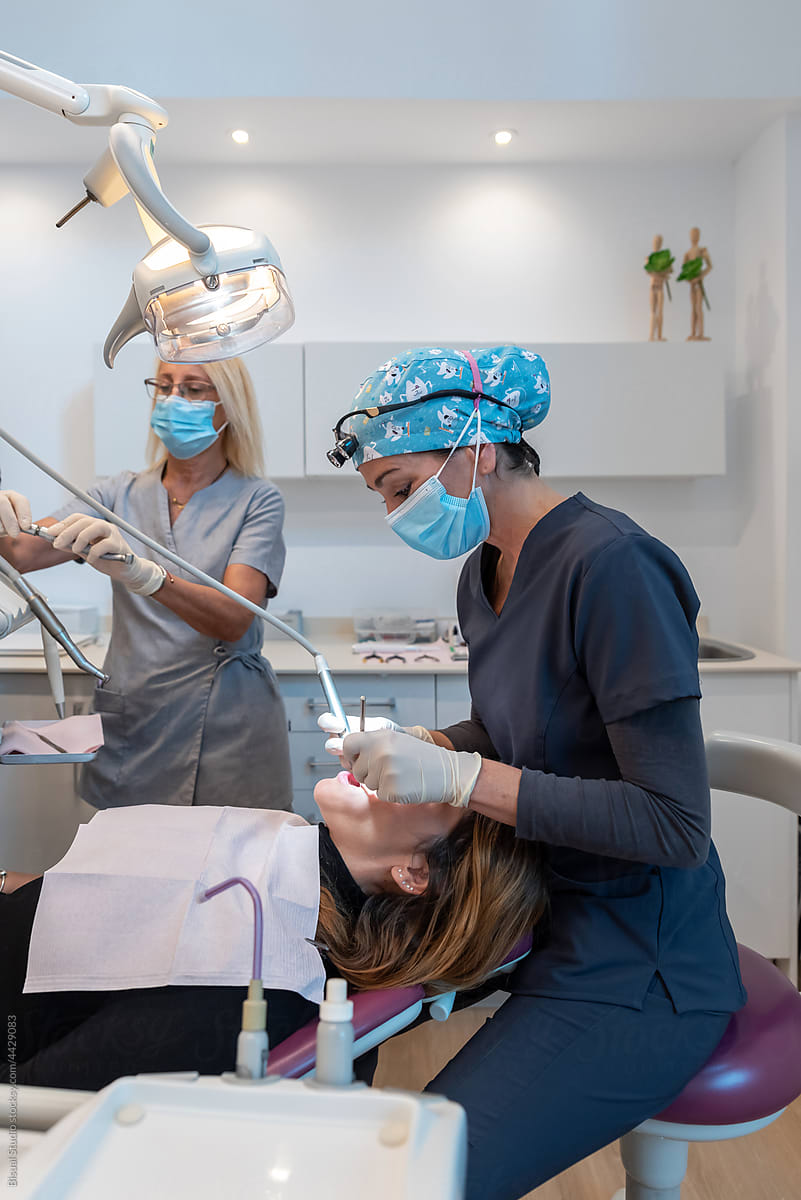 Professional dentists treating teeth of female patient