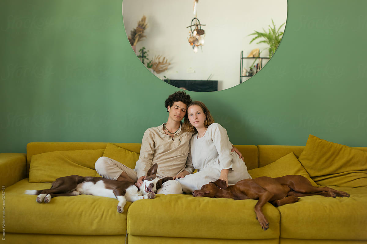 a couple with dogs sitting on the couch in the center