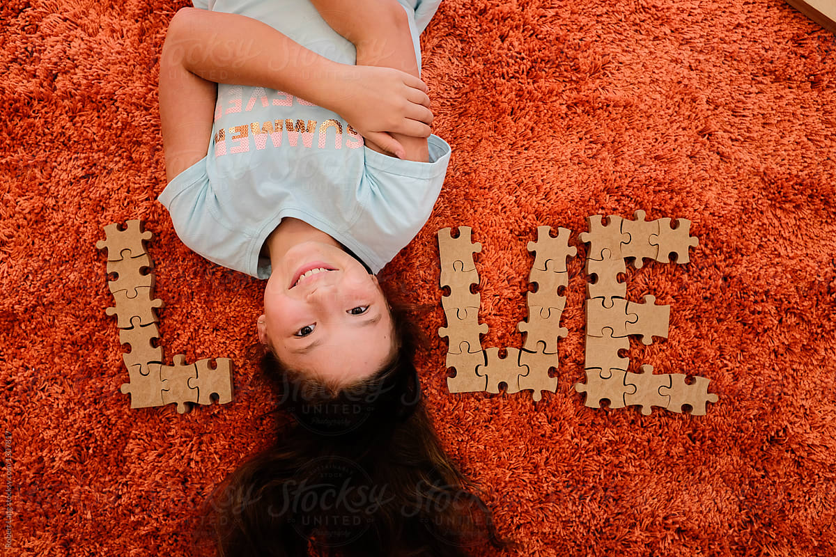 Young girl laying on floor with love spelled in puzzle pieces