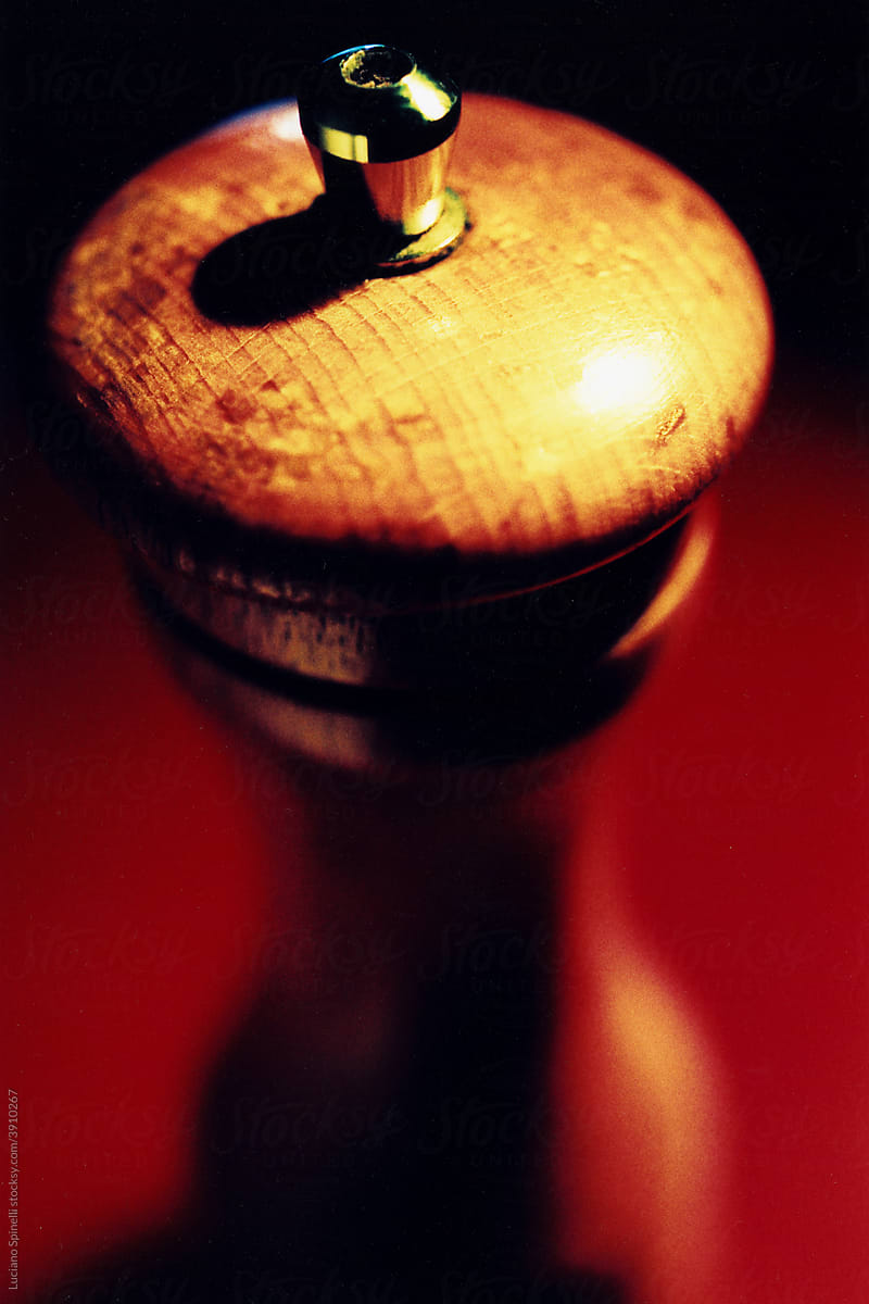 Detail shot of a wooden pepper mill with metal and red background