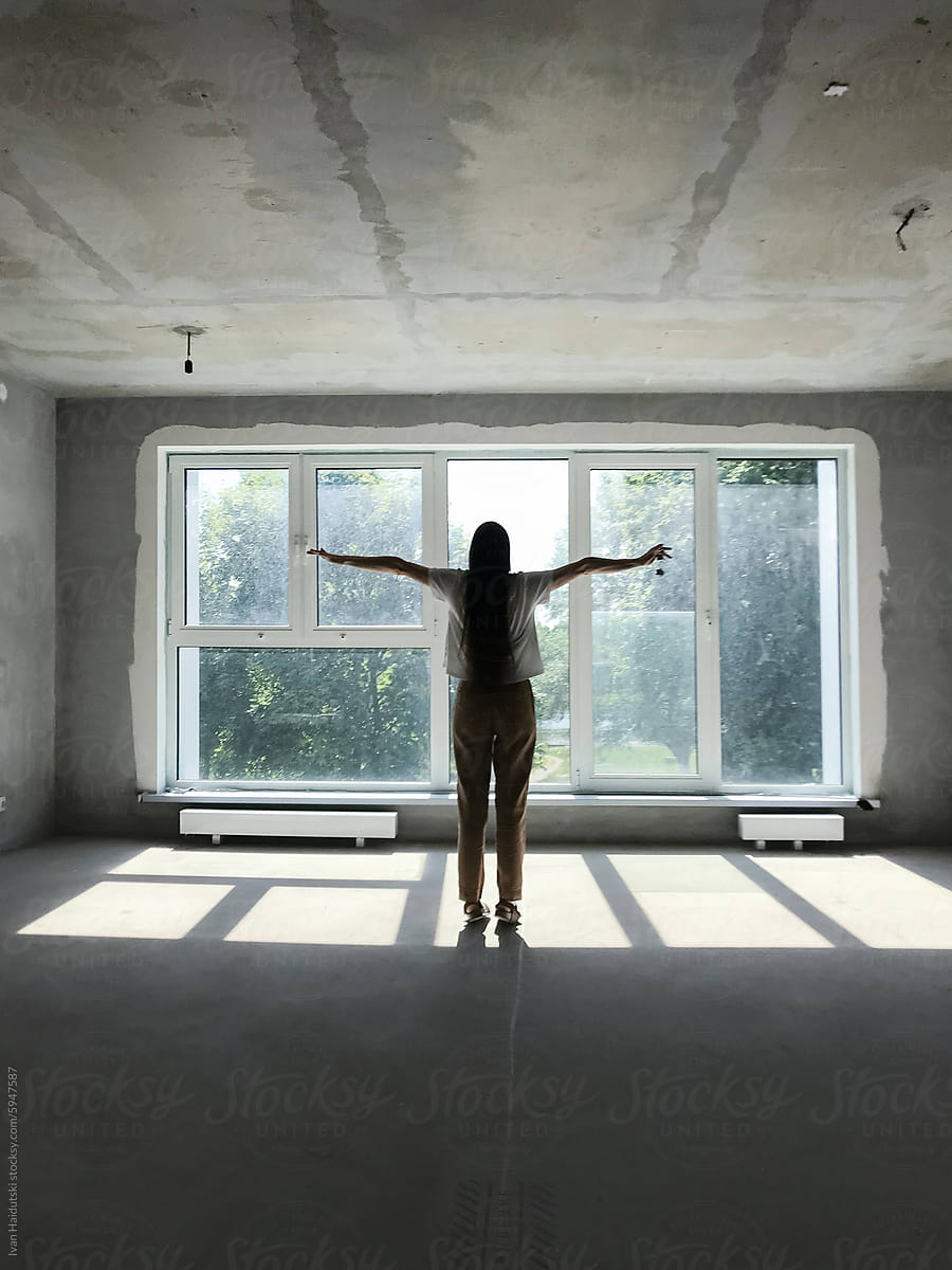 happy millennial woman in front of window in a new house