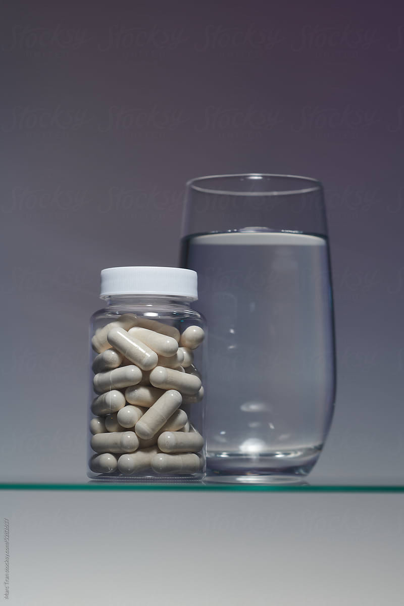 closed glass jar with pill capsules on a gray background