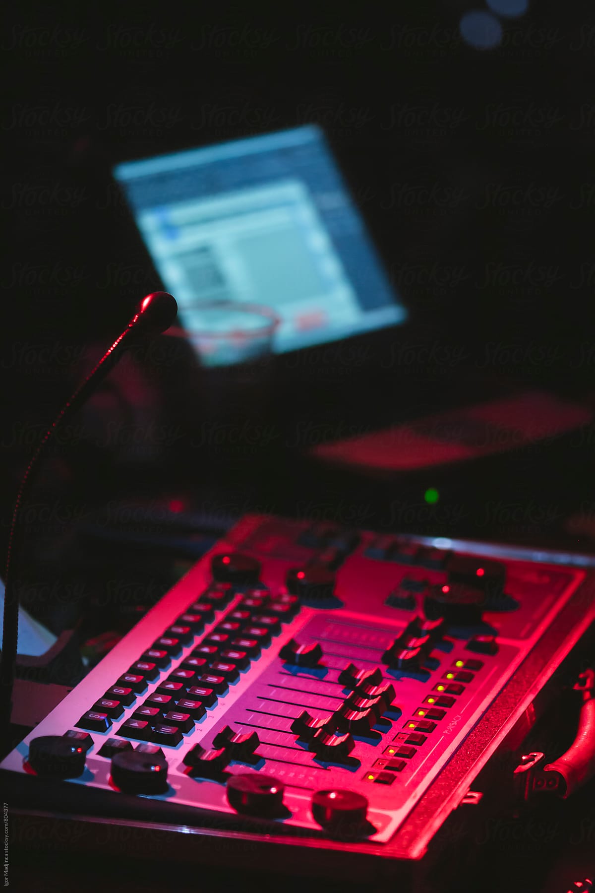 dj, computer,red lights,working on a sound mixer