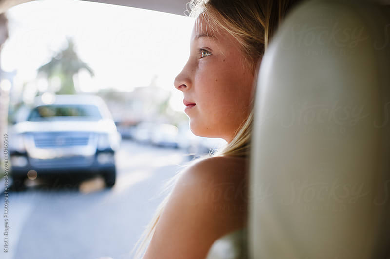 Young girl sitting in back of car with profile at golden hour