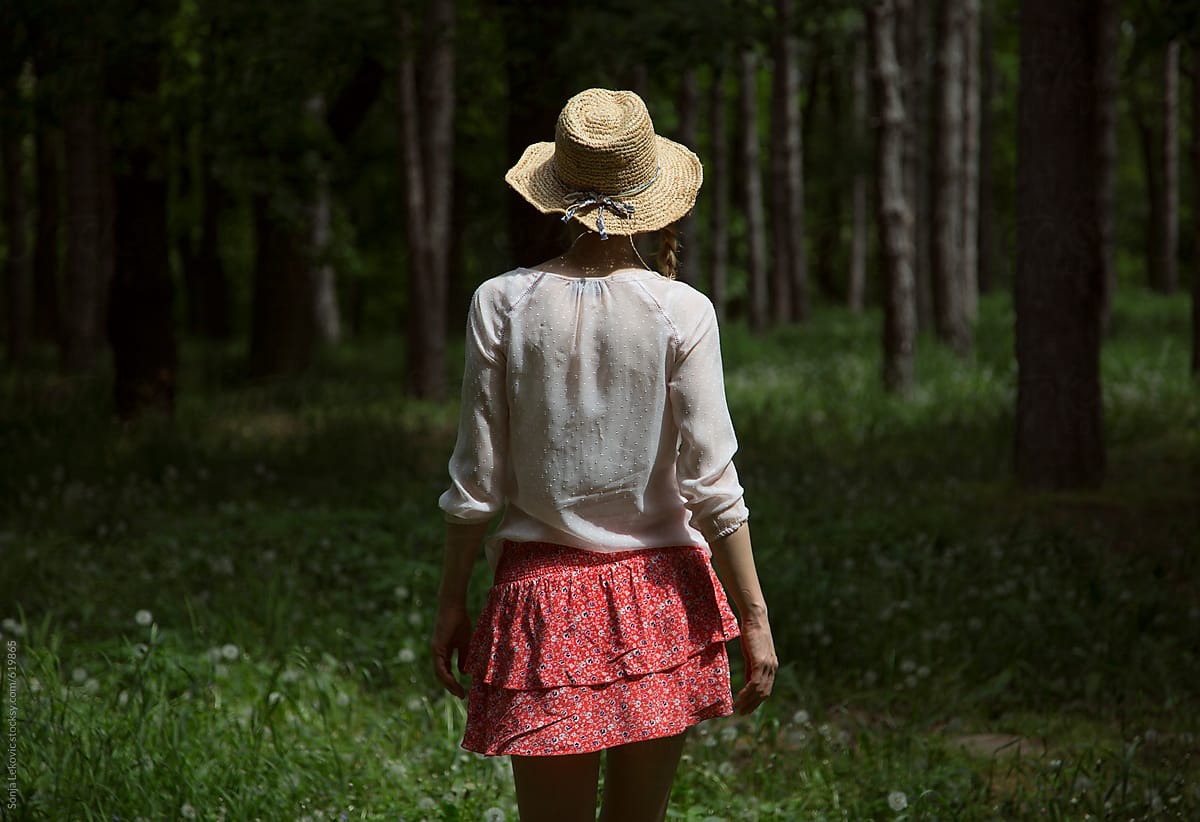 woman with a hat from the back in the woods