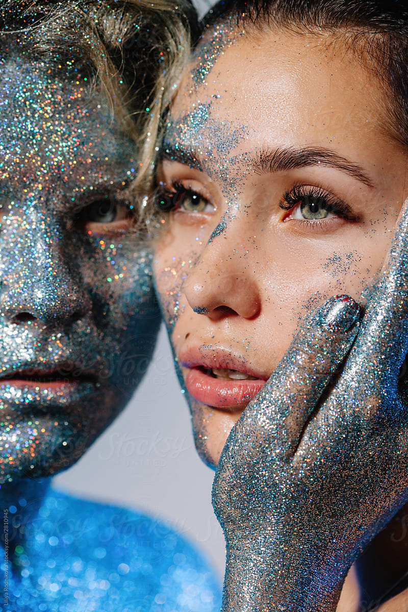 Closeup beauty portrait of two women with faces covered with glitter