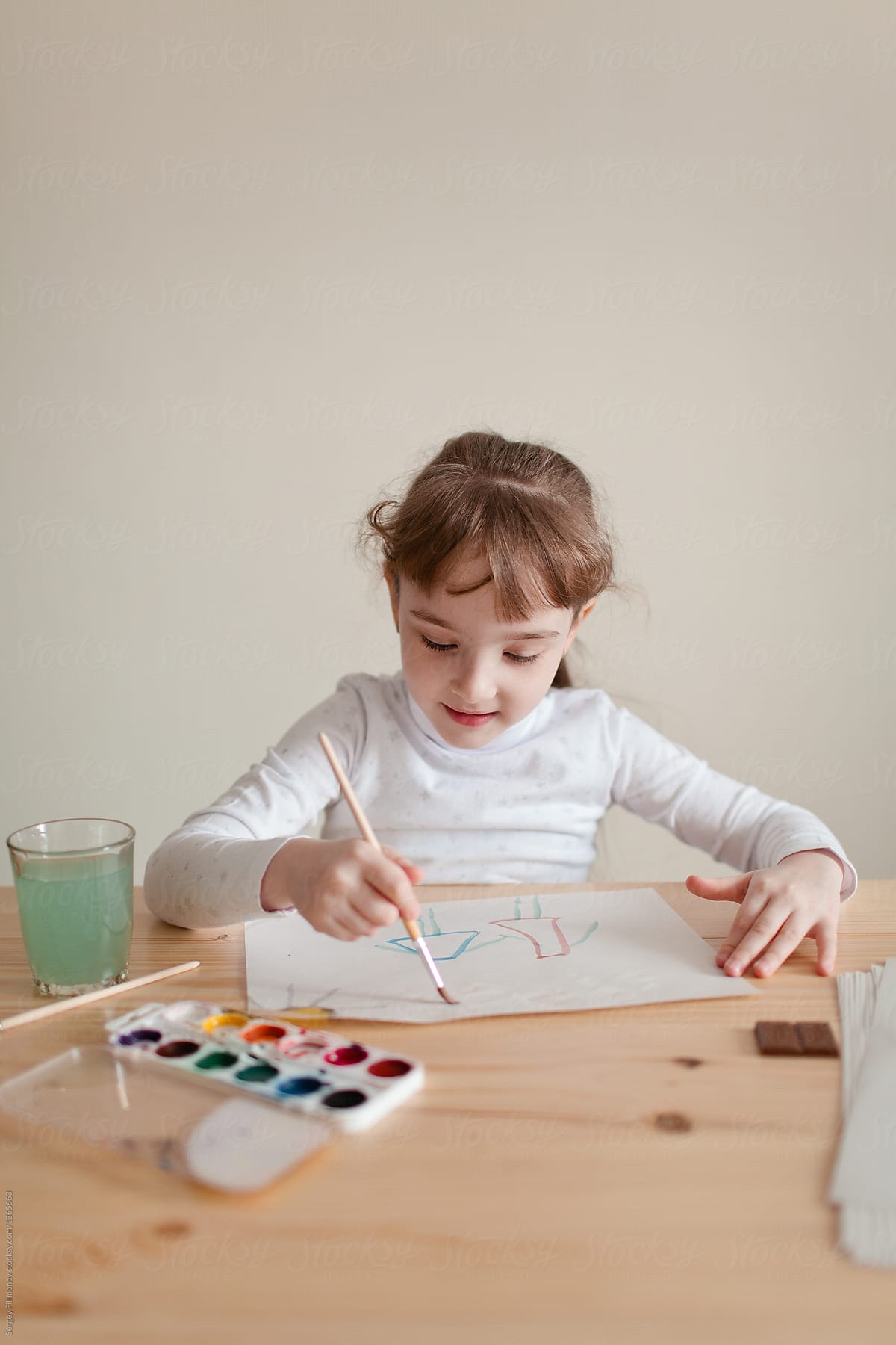 Little girl doing painting with watercolor