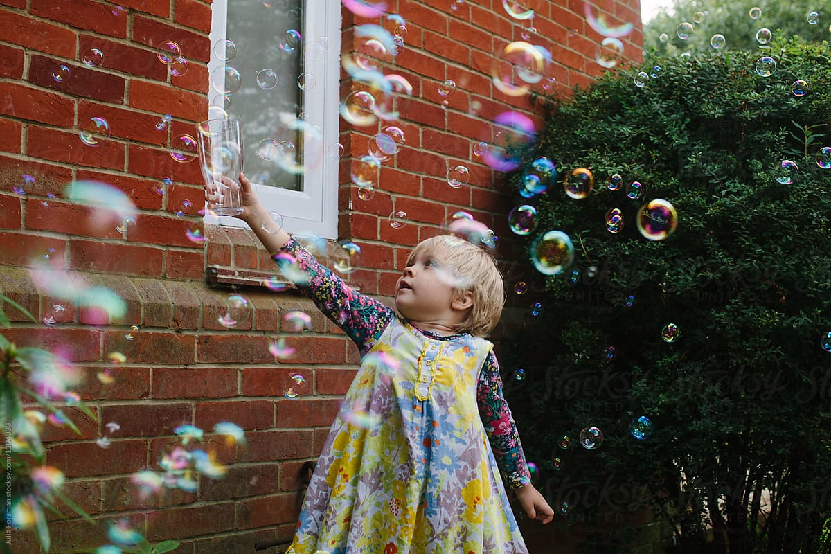 Little girl catches bubbles in a glass.