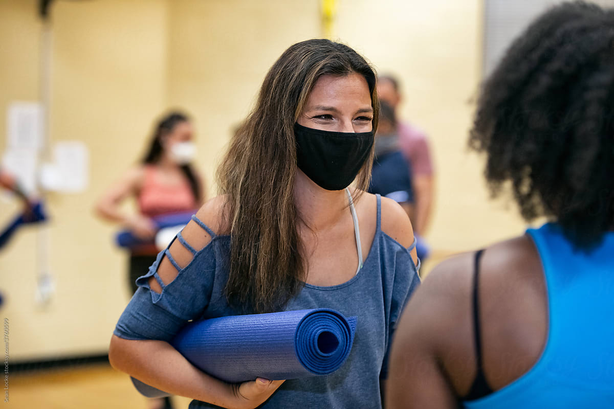 Gym Woman Talks With Instructor Before Stretching Class By Stocksy