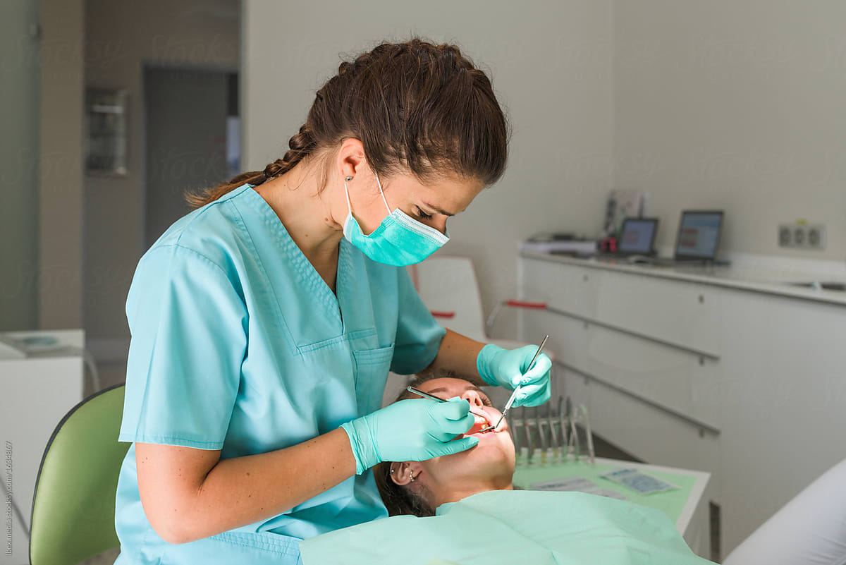 Female Orthodontist Examining Her Patient by Ibex.media - Dentist,  Orthodontist