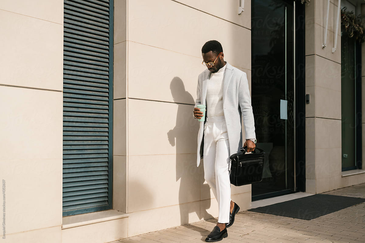 Stylish African American businessman walking on street