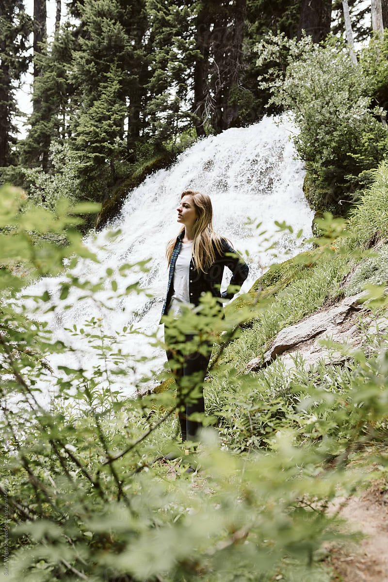 Young blonde woman standing in front of waterfall in Oregon