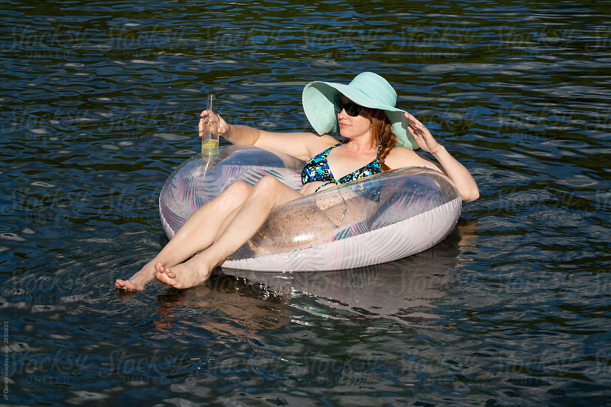Woman Floating on Inflatable with Drink Relaxing on Sunny Summer