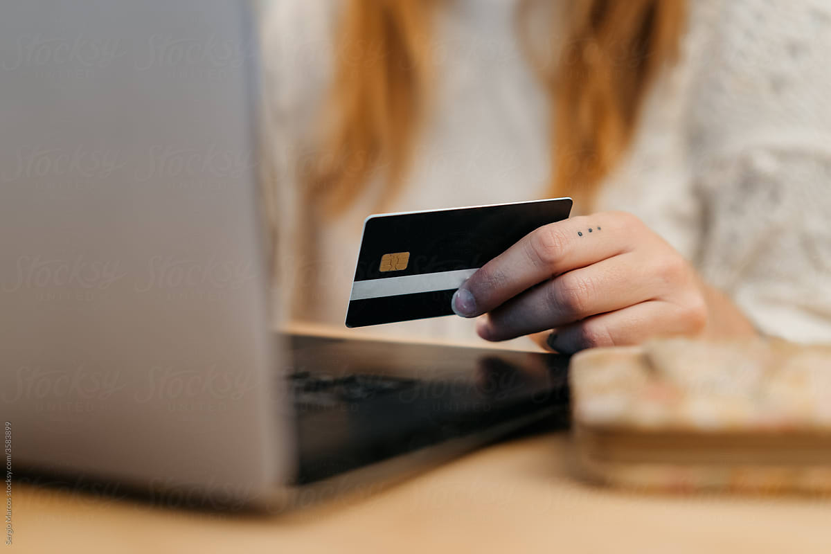 Close up of Unrecognizable woman online shopping with her laptop and paying with the credit card
