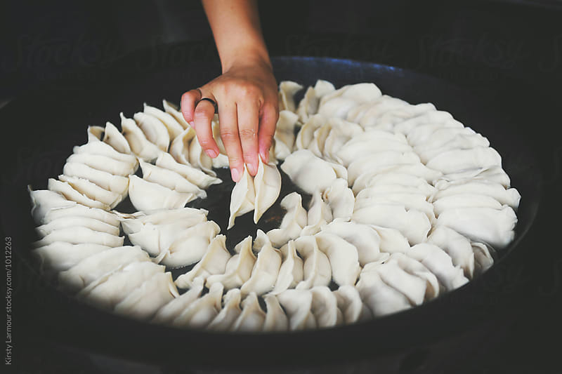 Woman placing dumplings in a pan in Shanghai China
