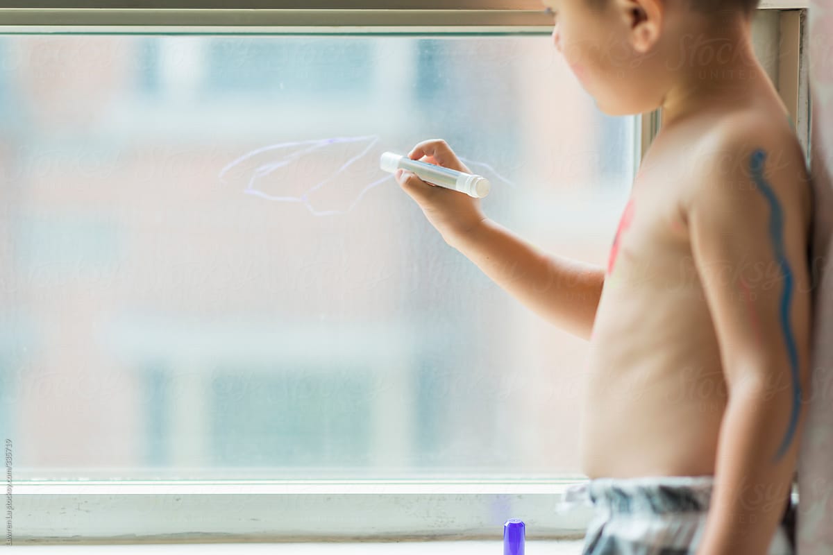 Kid drawing on glass of window
