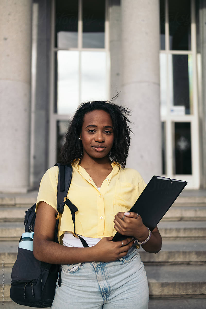 Portrait of a young student with backpack and folder outdoors