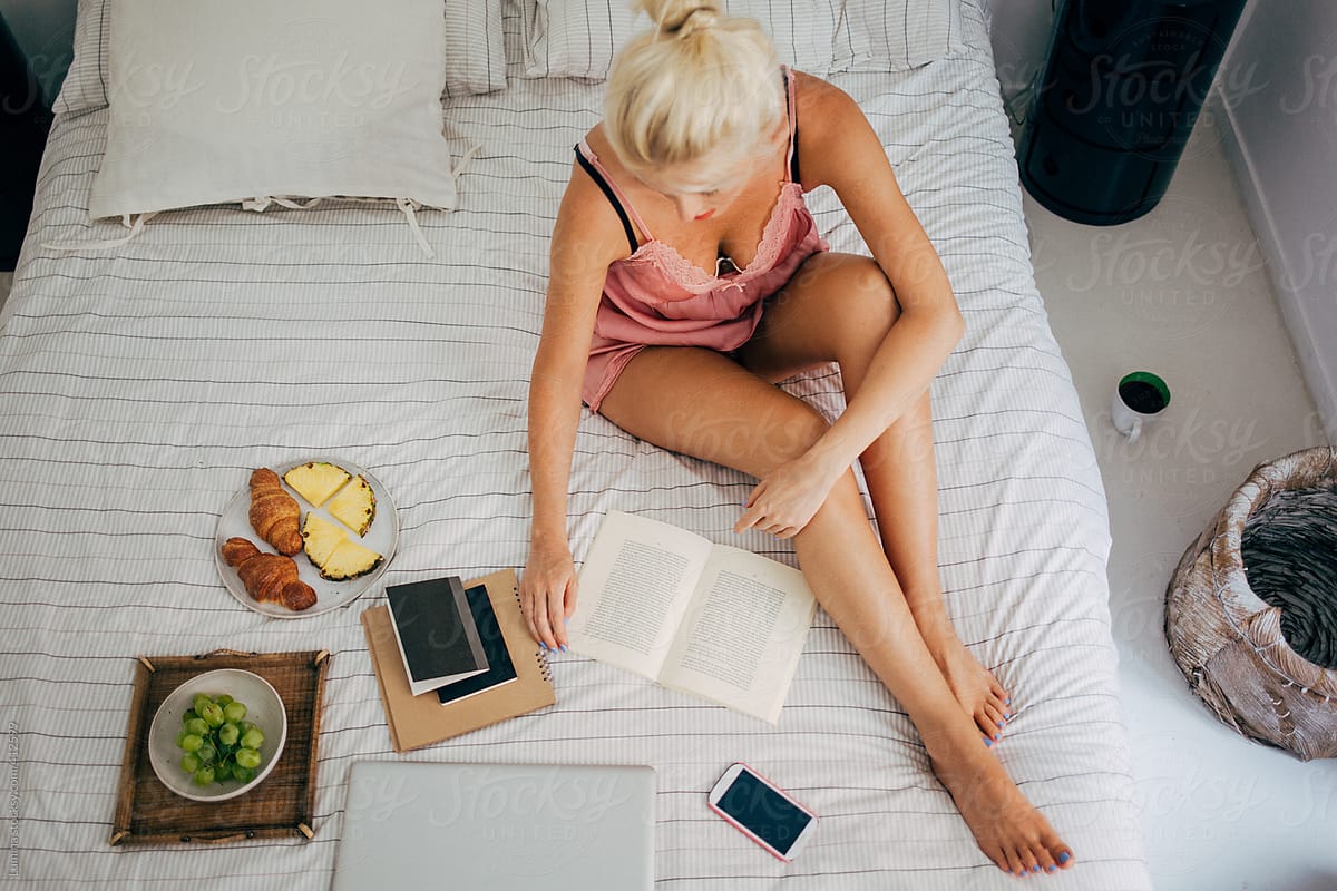 Caucasian Woman Reading a Book in Bed