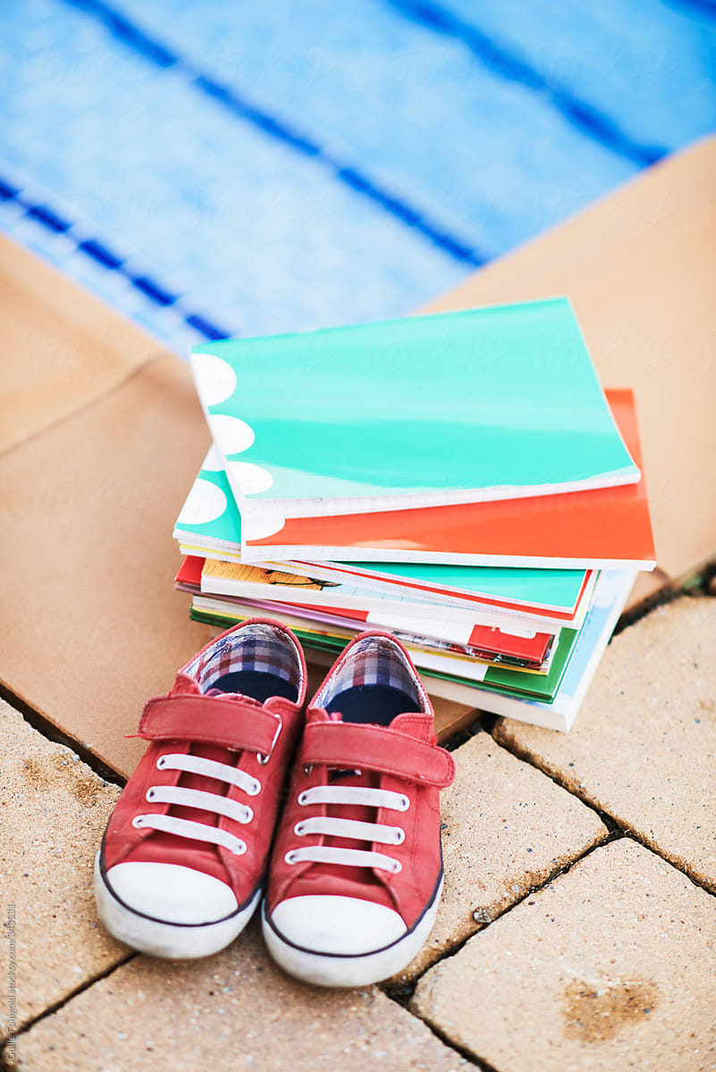 Sneakers and books by swimming pool