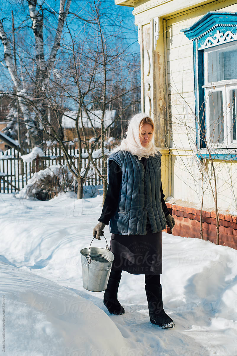 Woman carrying bucket of water in winter