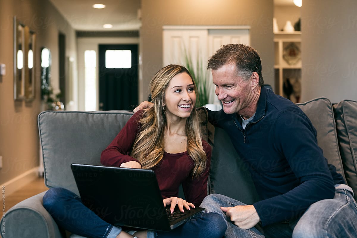 Home: Father And Daughter Laugh While Using Laptop