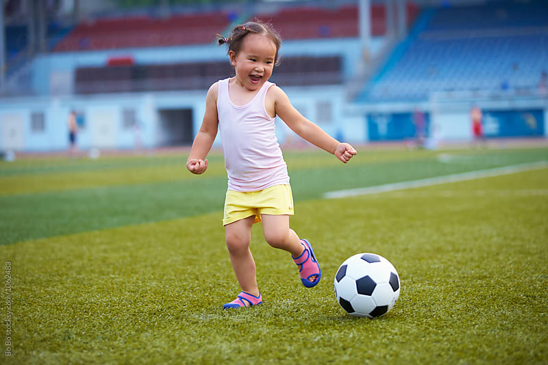 little girl playing football outdoor in the football field