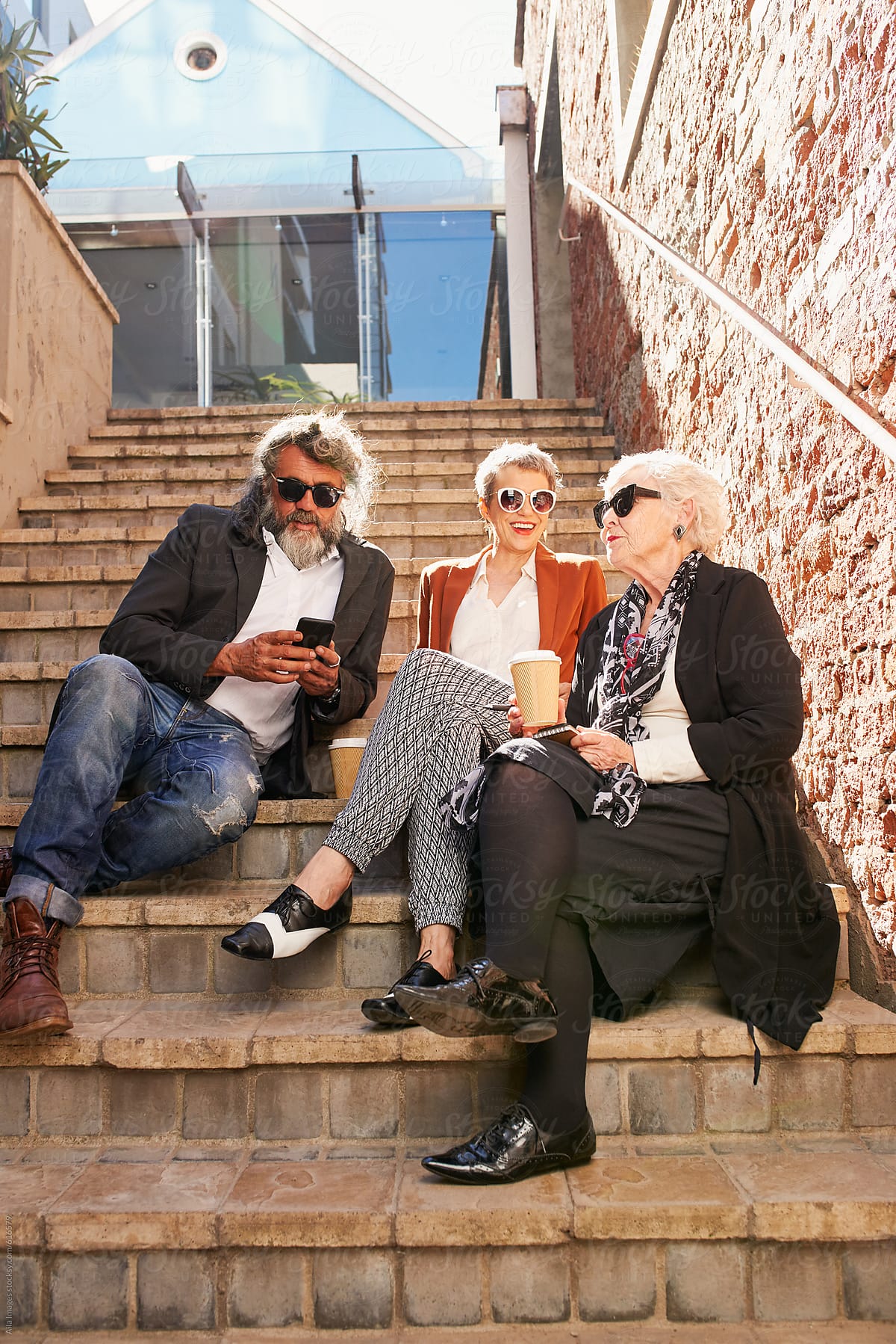 Three old friends enjoying the sun on the steps using digital tablet technology