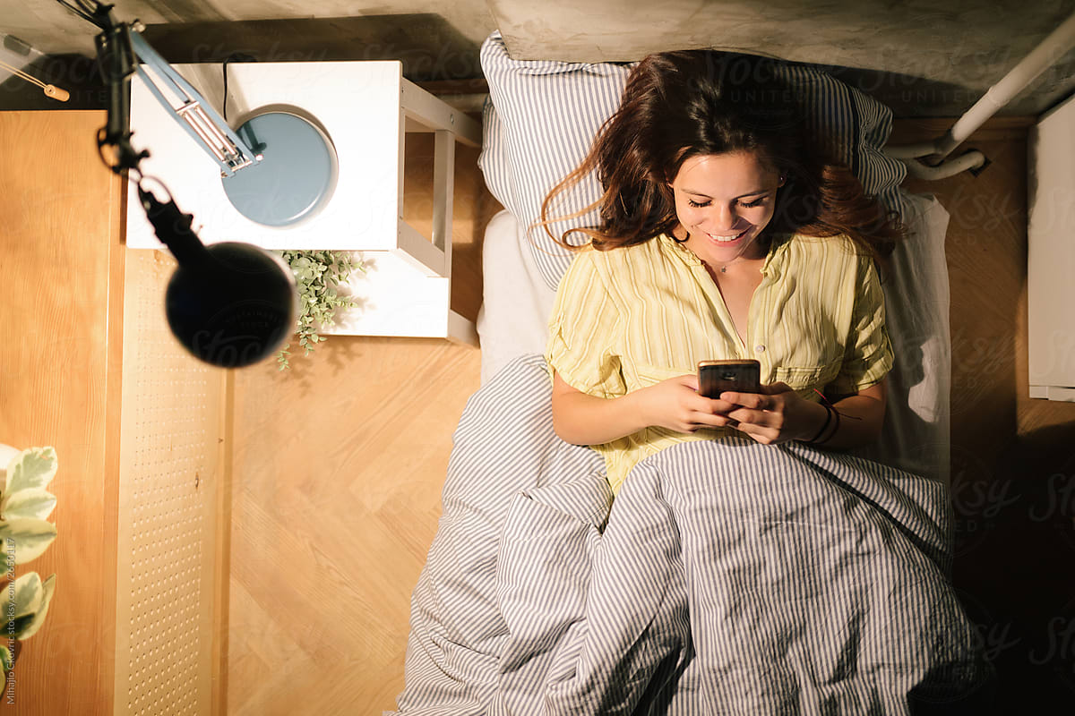 Young woman using her phone in bed