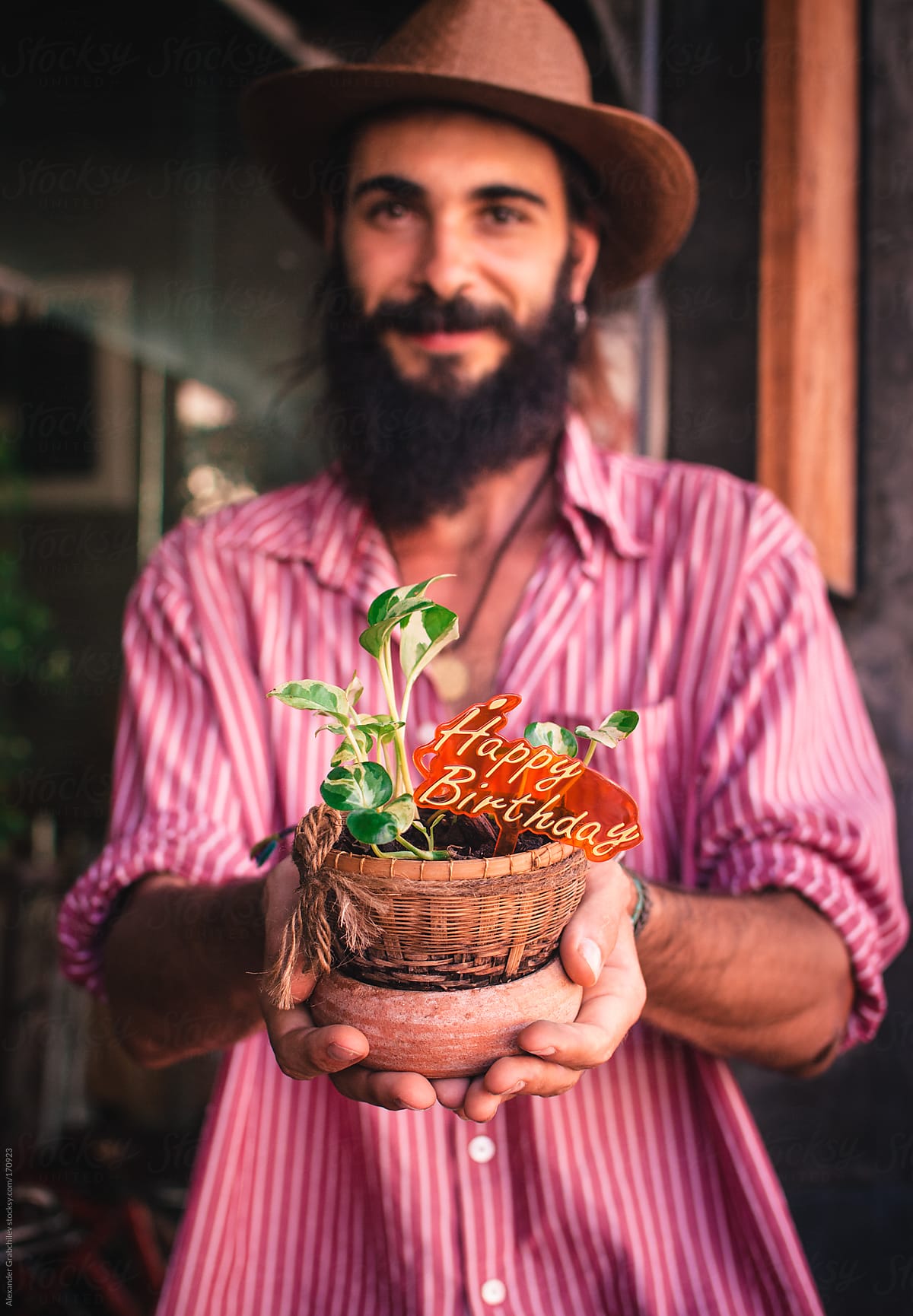 bearded young man holds flower pot
