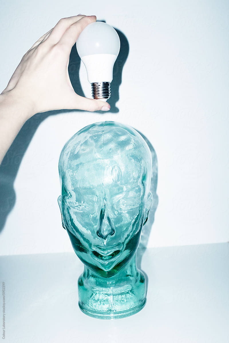 Glass head and light bulb representing new idea, ideation, eureka
