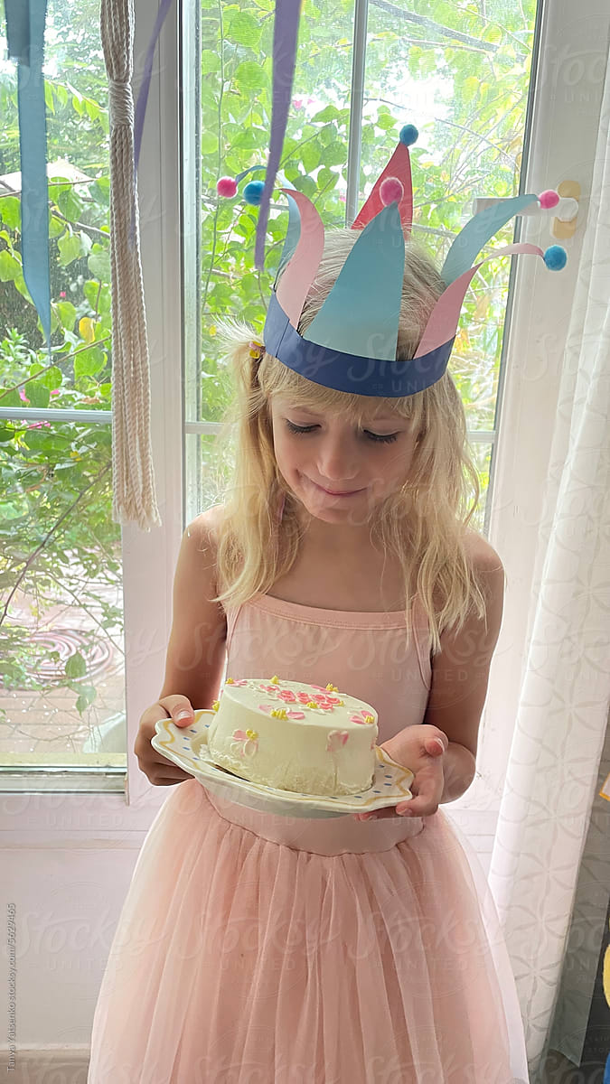 A girl with a birthday cake at home by the window