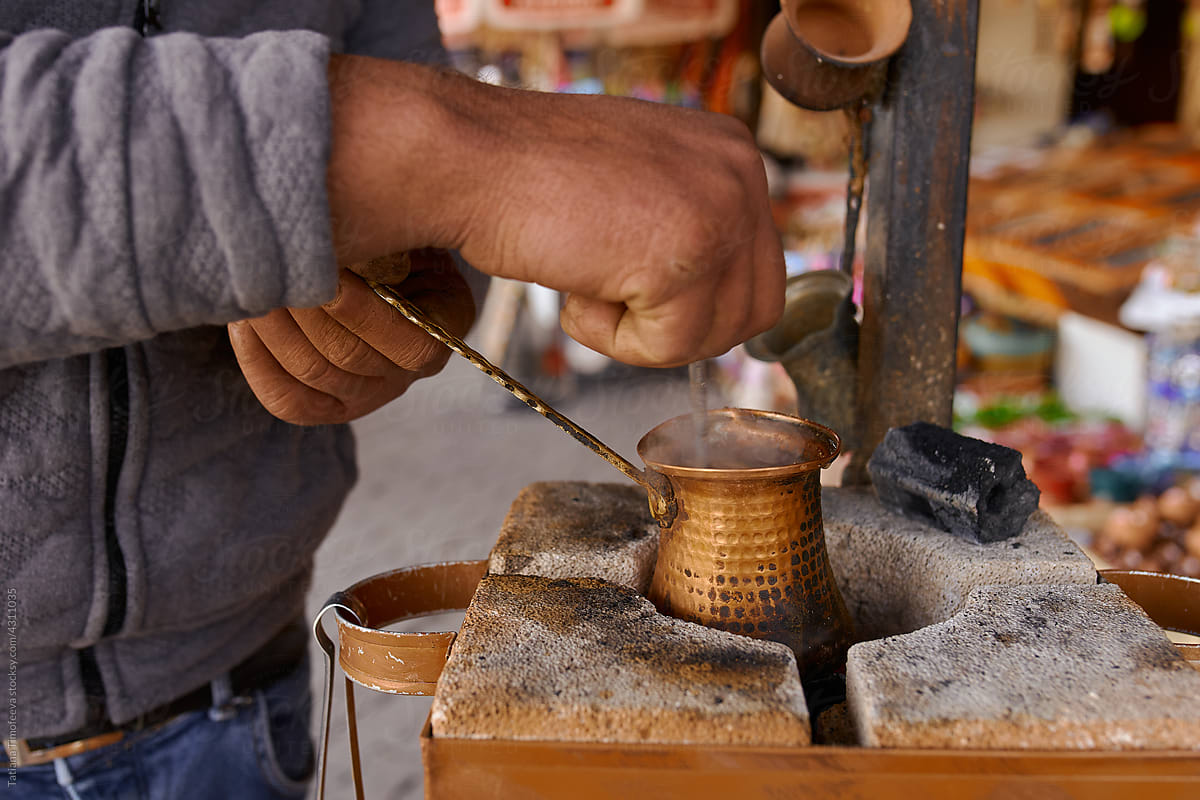 a man makes oriental coffee in a turk