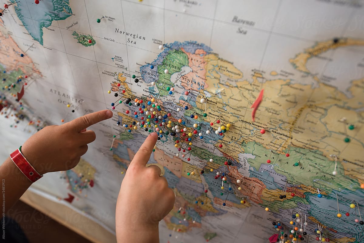 Two children point to a map where people have visited from around the world