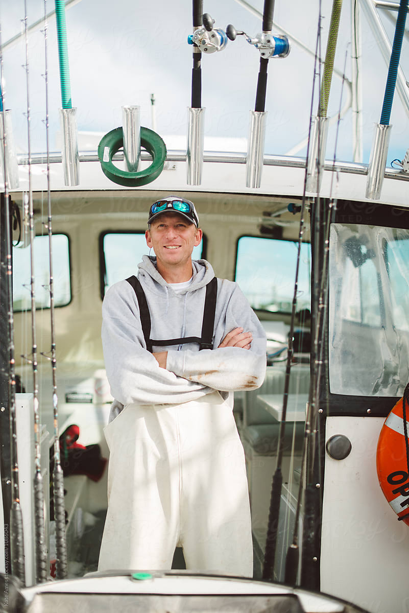 Proud commercial fisherman captain standing in doorway of cabin on his boat.