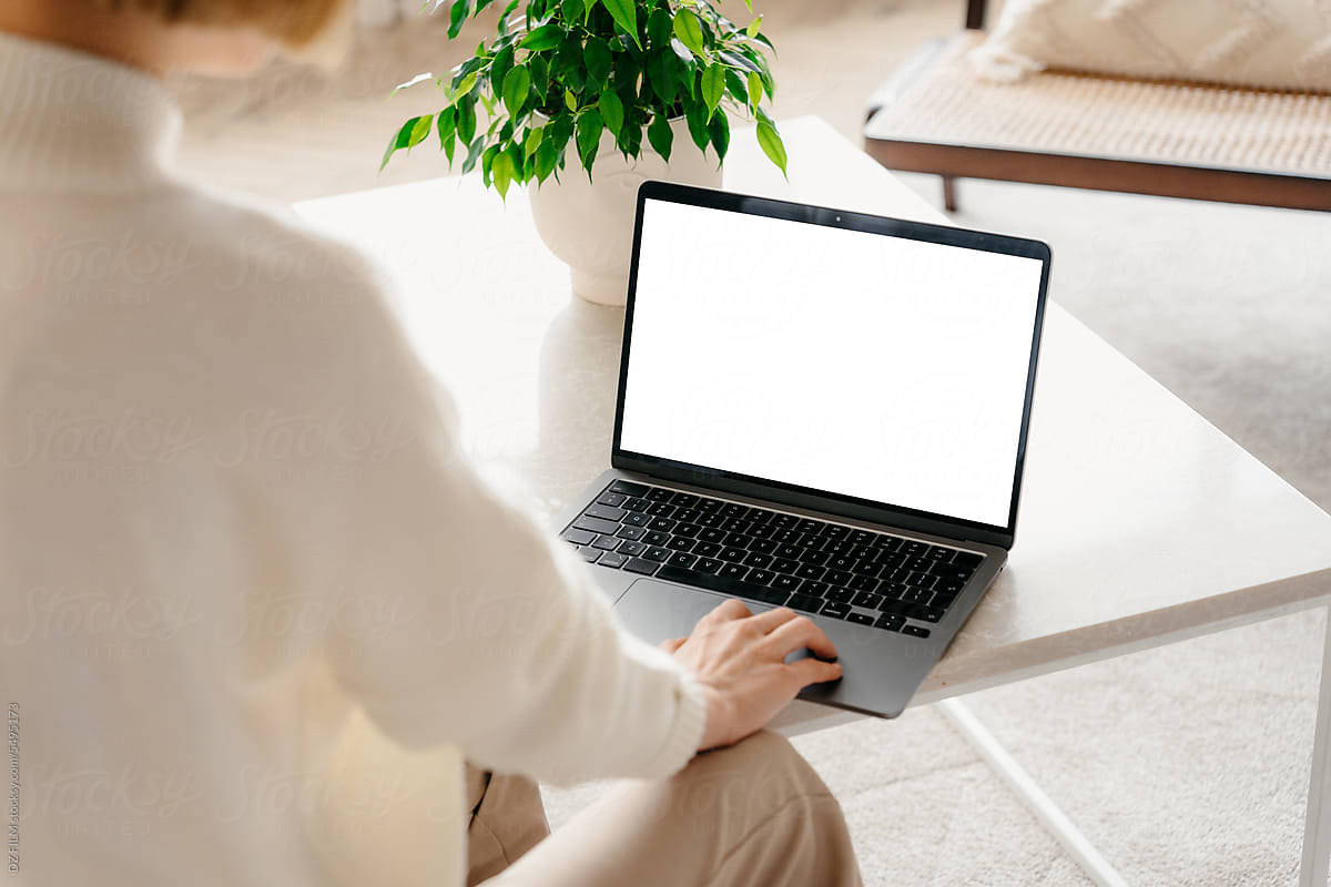 A woman uses a laptop with white screen