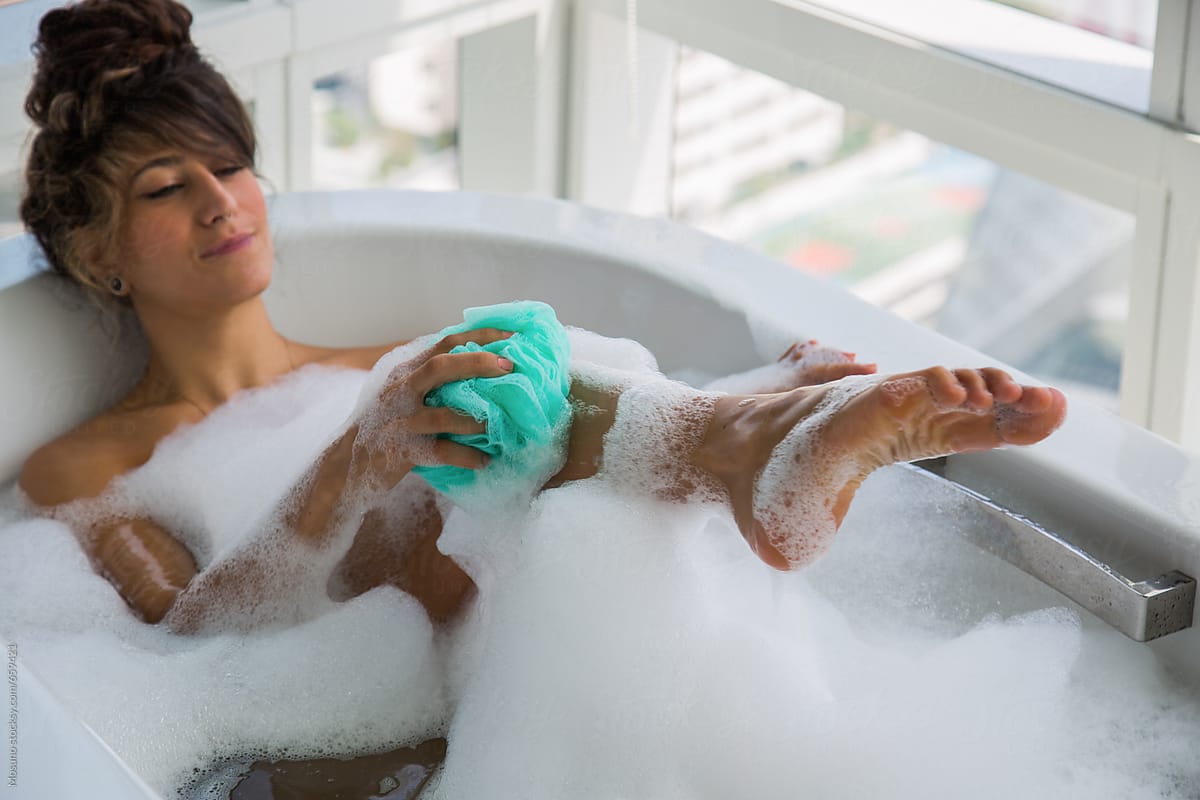 Woman Taking a Bath and Scrubbing With a Sponge