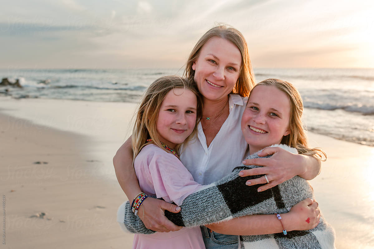 Portrait of mother holding her tween and teen daughters in her arms